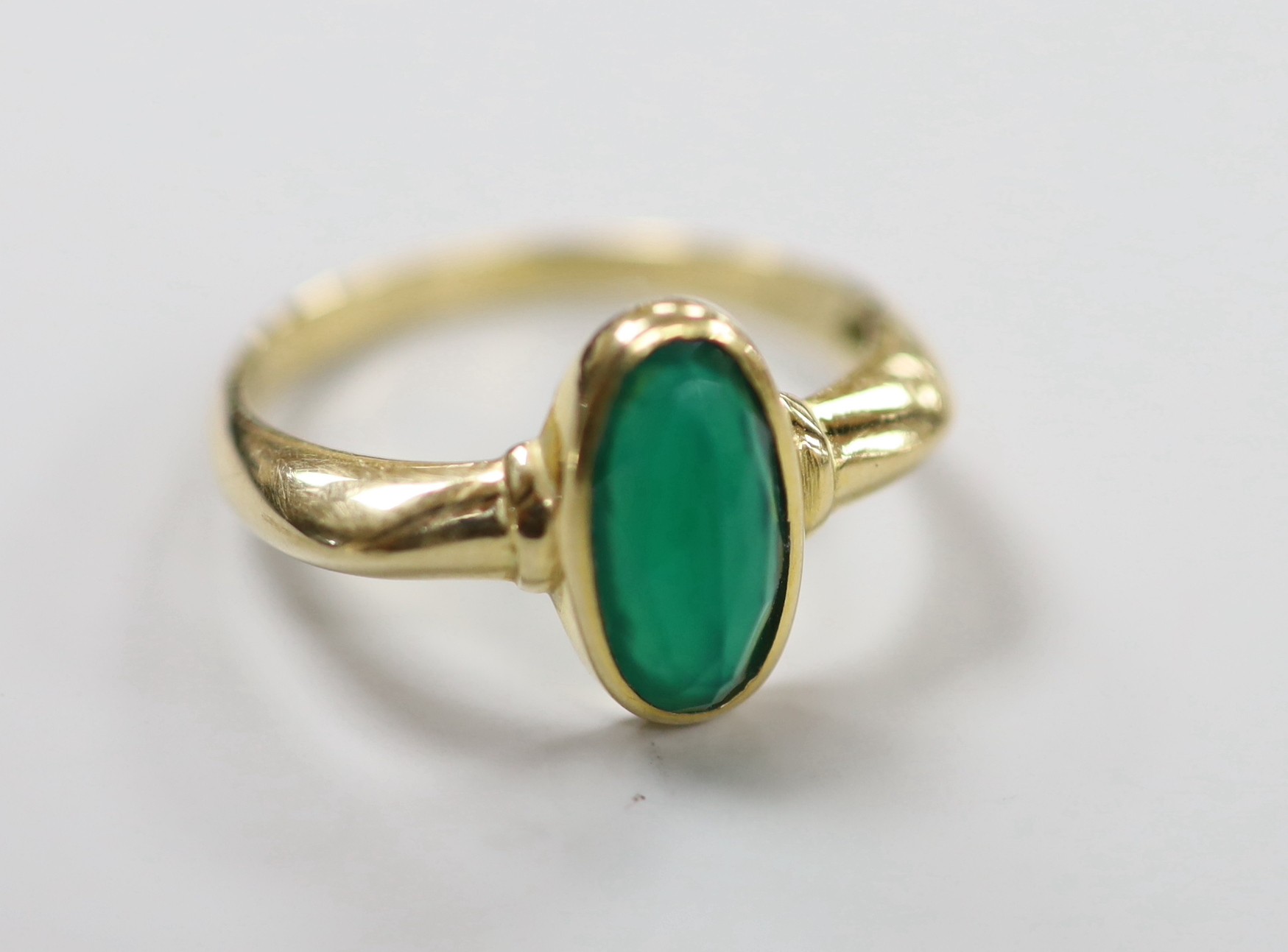 A modern yellow metal and single stone facetted oval chrysoprase set ring, size S, gross weight 3.7 grams.